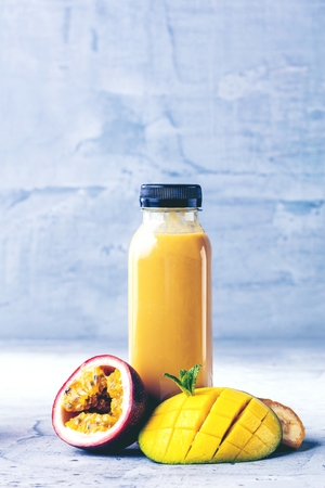 Flat-lay of colorful smoothies in bottles with fresh tropical fruit and superfoods on concrete background.の写真素材