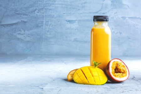 Flat-lay of colorful smoothies in bottles with fresh tropical fruit and superfoods on concrete background.の写真素材
