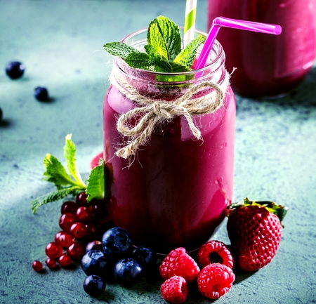 Flat-lay of colorful smoothies in bottles with fresh tropical fruit and superfoods on concrete background.の写真素材