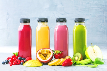Flat-lay of colorful smoothies in bottles with fresh tropical fruit and superfoods on concrete background.の写真素材