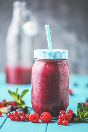 Flat-lay of colorful smoothies in bottles with fresh tropical fruit and superfoods on concrete background.の写真素材