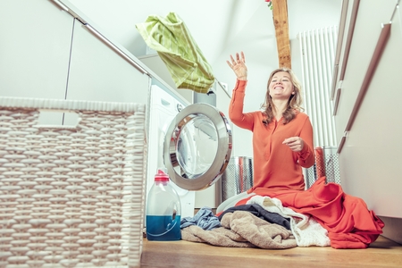 Young housewife is doing laundry with washing machine at homeの写真素材
