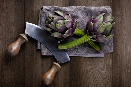 Natural artichokes on a rustic wooden table close up.の写真素材