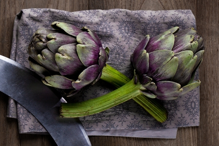 Natural artichokes on a rustic wooden table close up.の写真素材