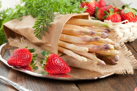White asparagus and strawberries on wooden table.の写真素材