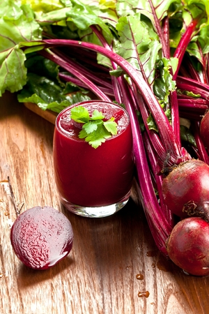Glass of fresh beetroot juice with bets on wooden tableの写真素材