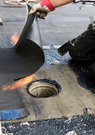 Flat roof installation. Heating and melting bitumen roofing felt.の写真素材
