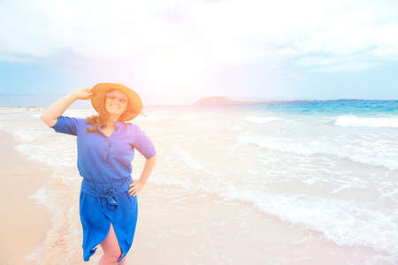 Happy traveler woman in blue dress enjoys her tropical beach vacationの写真素材