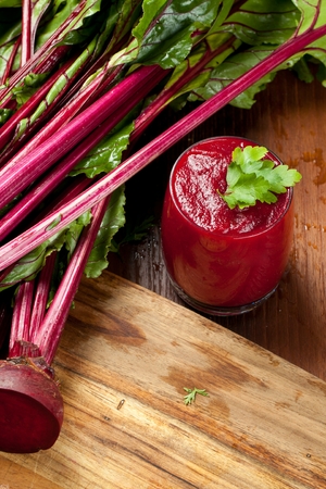 Glass of fresh beetroot juice with bets on wooden tableの写真素材