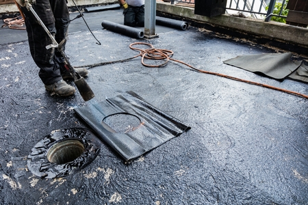 Flat roof installation. Heating and melting bitumen roofing felt.の写真素材