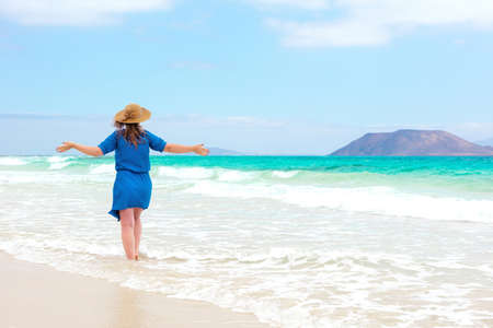 Happy traveler woman in blue dress enjoys her tropical beach vacationの写真素材