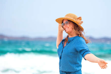 Happy traveler woman in blue dress enjoys her tropical beach vacationの写真素材