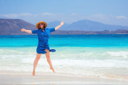 Happy traveler woman in blue dress enjoys her tropical beach vacationの写真素材