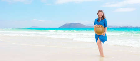 Happy traveler woman in blue dress enjoys her tropical beach vacationの写真素材