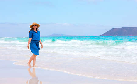 Happy traveler woman in blue dress enjoys her tropical beach vacationの写真素材