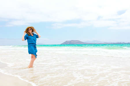 Happy traveler woman in blue dress enjoys her tropical beach vacationの写真素材