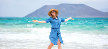 Happy traveler woman in blue dress enjoys her tropical beach vacationの写真素材