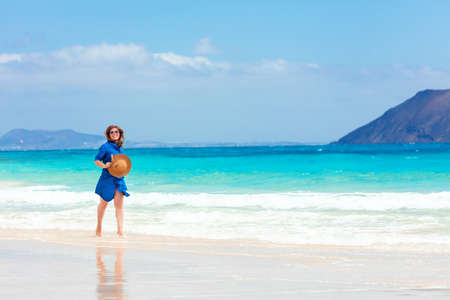 Happy traveler woman in blue dress enjoys her tropical beach vacationの写真素材