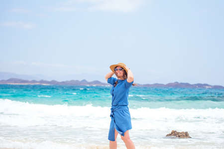 Happy traveler woman in blue dress enjoys her tropical beach vacation