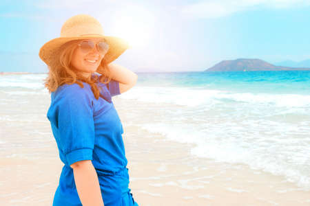 Happy traveler woman in blue dress enjoys her tropical beach vacationの写真素材