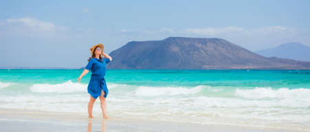 Happy traveler woman in blue dress enjoys her tropical beach vacationの写真素材