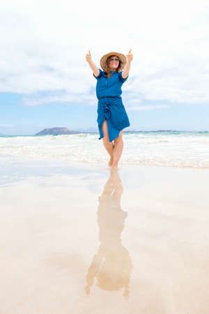 Happy traveler woman in blue dress enjoys her tropical beach vacationの写真素材