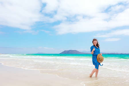 Happy traveler woman in blue dress enjoys her tropical beach vacationの写真素材