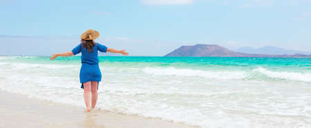 Happy traveler woman in blue dress enjoys her tropical beach vacationの写真素材