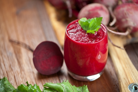 Glass of fresh beetroot juice with bets on wooden tableの写真素材