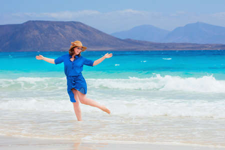 Happy traveler woman in blue dress enjoys her tropical beach vacationの写真素材