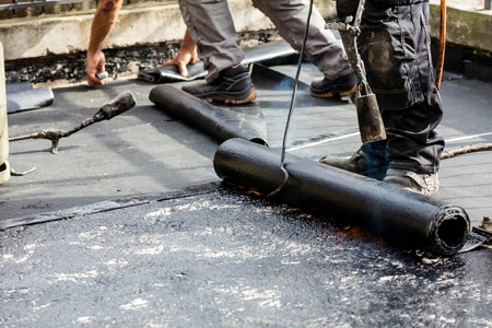 Flat roof installation. Heating and melting bitumen roofing felt.の写真素材
