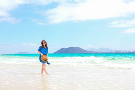Happy traveler woman in blue dress enjoys her tropical beach vacationの写真素材