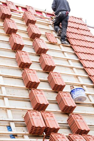 Roofer working on roof structure of building on construction site.の写真素材