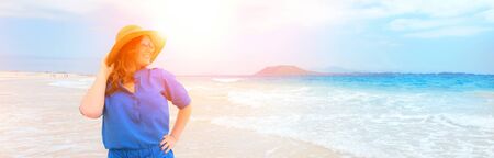 Happy traveler woman in blue dress enjoys her tropical beach vacationの写真素材
