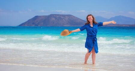 Happy traveler woman in blue dress enjoys her tropical beach vacationの写真素材