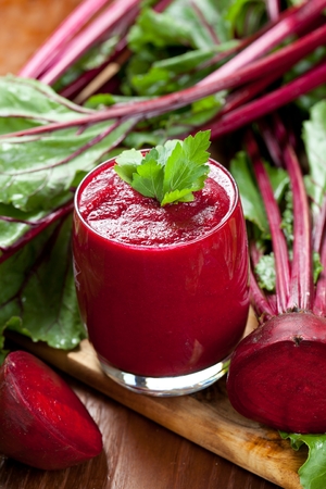 Glass of fresh beetroot juice with bets on wooden tableの写真素材