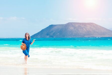 Happy traveler woman in blue dress enjoys her tropical beach vacationの写真素材
