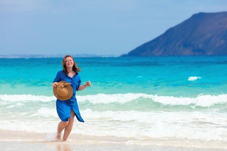 Happy traveler woman in blue dress enjoys her tropical beach vacationの写真素材