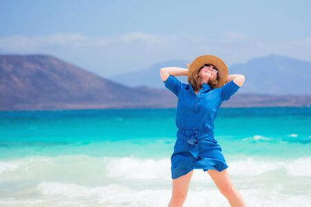 Happy traveler woman in blue dress enjoys her tropical beach vacationの写真素材
