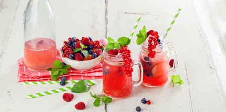 Summer Berry Drink. Lemonade with raspberry and blackberry with lemon, mint in mason jar on white table .の写真素材