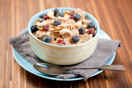 Bowl of homemade granola with yogurt and fresh berries on wooden background from top view.