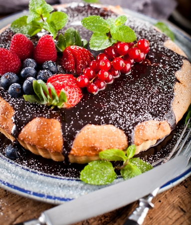 Delicious tart with fresh strawberries, raspberries and currants on the tableの写真素材