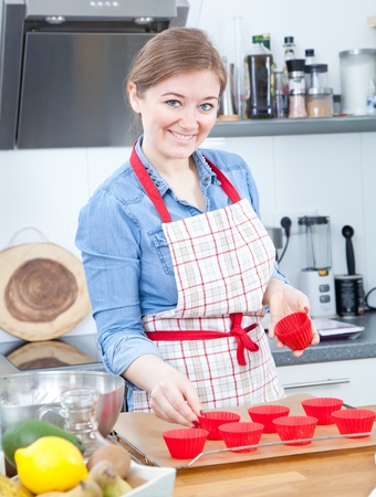 Pretty young woman baking tasty muffins at home.の写真素材