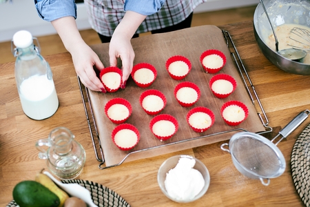 Pretty young woman baking tasty muffins at home.