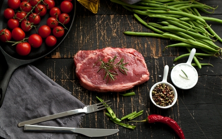 Raw Steak with ingredients on wooden cut board.の写真素材
