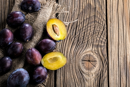Plums ripe fresh on the wood texture backgroundの写真素材
