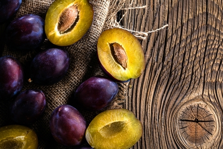 Plums ripe fresh on the wood texture backgroundの写真素材
