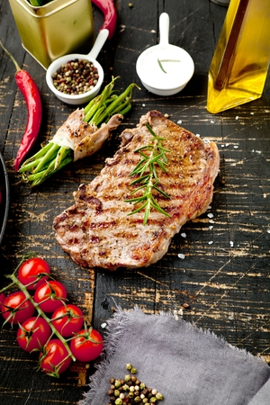 Fresh grilled meat. Grilled beef steak medium rare on wooden cutting board. Top view.の写真素材