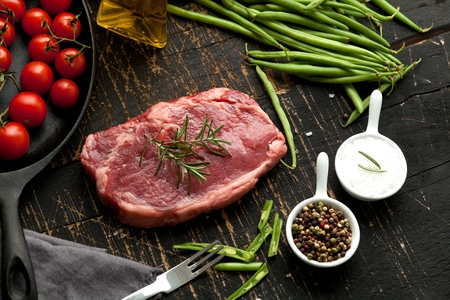 Raw Steak with ingredients on wooden cut board.の写真素材