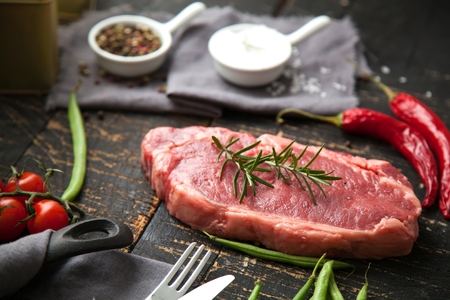 Raw Steak with ingredients on wooden cut board.の写真素材